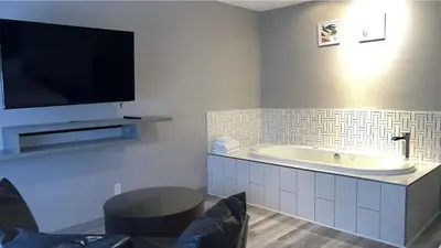 a bathroom with a tub and a tv on the wall at Hotel Newstar Montréal in Montréal