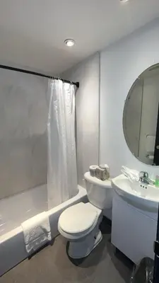 a white bathroom with a toilet and a sink at Hotel Newstar Montréal in Montréal