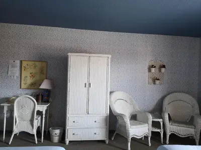 a room with chairs and a white cabinet and a table at Hotellerie Jardins de Ville in Sherbrooke