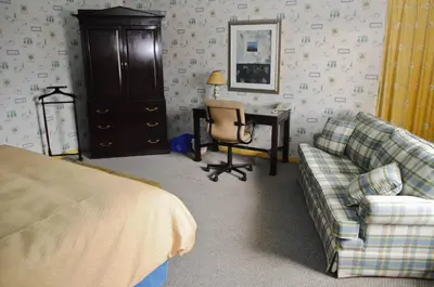 a bedroom with a bed and a desk and a couch at Hotellerie Jardins de Ville in Sherbrooke