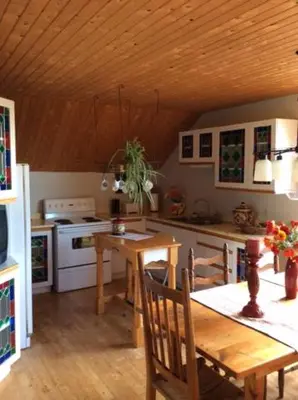 a kitchen with a wooden table and a wooden ceiling at La Maison Pamaljolie in Ayer's Cliff