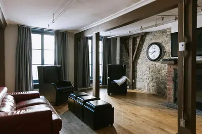 a living room with a couch and a clock on the wall at Lofts du Vieux-Port by Gray Collection in Montréal