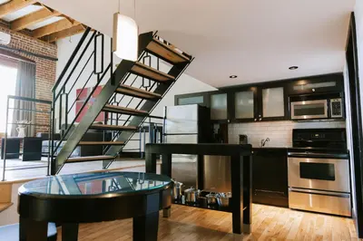 a kitchen with a glass table and a spiral staircase at Lofts du Vieux-Port by Gray Collection in Montréal