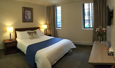 a hotel room with a bed and two windows at Hotel Le Deville in Montréal