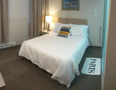 a bedroom with a large white bed with a welcome mat at Hotel Le Deville in Montréal