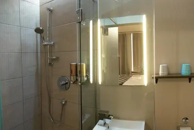 a bathroom with a shower with a sink and a mirror at Hotel Le Deville in Montréal