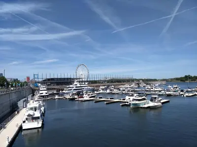 a bunch of boats docked in a harbor with a ferris wheel at Hotel Le Deville in Montréal