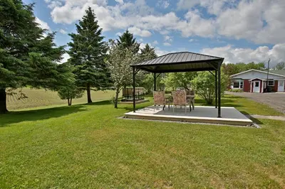 a gazebo with a table and chairs in a yard at Motel Exquise in Coaticook