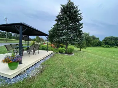 a patio with chairs and a table and a tree at Motel Exquise in Coaticook