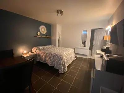 a bedroom with a bed with a checkered blanket at Motel Exquise in Coaticook
