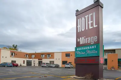 a sign for a hotel in a parking lot at Hotel Le Mirage in Saint-Basile-le-Grand