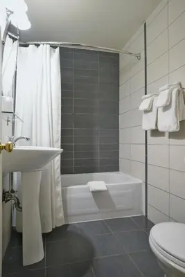 a bathroom with a tub and a sink and a toilet at Hotel Le Mirage in Saint-Basile-le-Grand