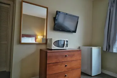 a room with a television and a dresser with a tv on the wall at Hotel Le Mirage in Saint-Basile-le-Grand