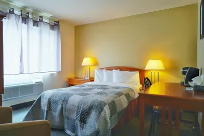 a hotel room with a bed and a desk and a window at Hotel Le Mirage in Saint-Basile-le-Grand