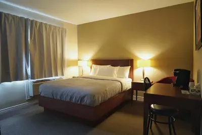 a hotel room with a bed and a desk and a desk at Hotel Le Mirage in Saint-Basile-le-Grand