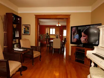 a living room with a television and a piano at Au Virage B&B in Magog-Orford