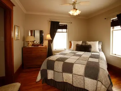 a bedroom with a bed and a dresser and windows at Au Virage B&B in Magog-Orford