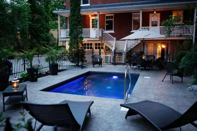 a patio with a swimming pool in front of a house at Au Virage B&B in Magog-Orford