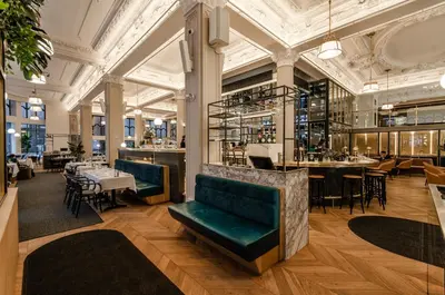 a restaurant with green velvet couches and a bar at Hôtel Birks Montréal in Montréal