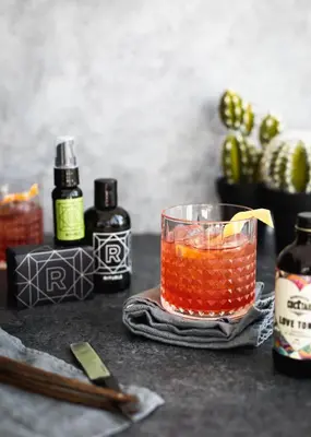 a drink sitting on a table with bottles of alcohol at Hôtel Escad Quartier DIX30 in Brossard