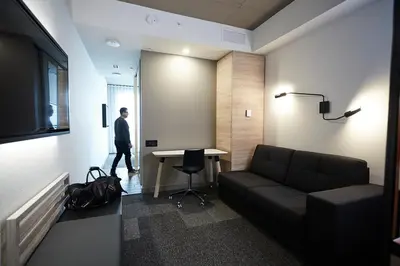 a man in a room with a couch and a table at Hôtel Escad Quartier DIX30 in Brossard