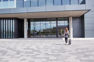 a woman walking in front of a building with a suitcase at Hôtel Escad Quartier DIX30 in Brossard