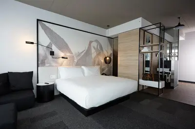 a bedroom with a large white bed and a couch at Hôtel Escad Quartier DIX30 in Brossard