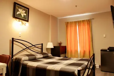 a bedroom with a bed and a window with an orange curtain at Hotel Victor in Montréal