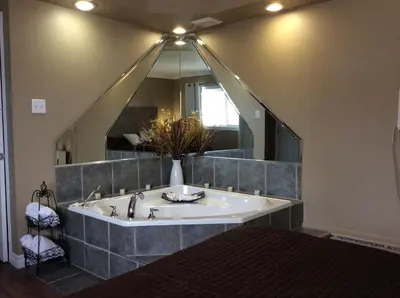 a bathroom with a tub with a large mirror at Miami Motel inc in Trois-Rivières