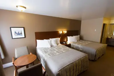 a hotel room with two beds and a table at Motel Invitation in Sainte-Marie