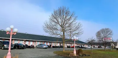 a parking lot with cars parked in front of a building at Motel Invitation in Sainte-Marie