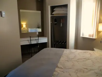 a bedroom with a bed and a desk and a mirror at Motel Invitation in Sainte-Marie