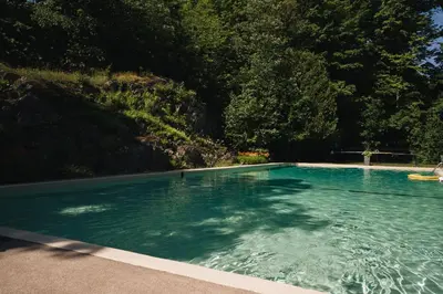 a swimming pool with blue water and trees at Domaine Jolivent in Lac-Brome