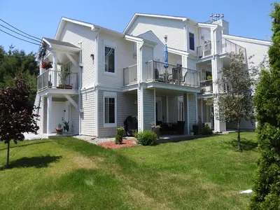 a large white house with a yard at Condo Entre Ville/Nature in Magog-Orford