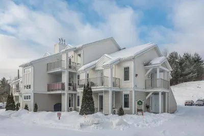 a large house with snow on the ground at Condo Entre Ville/Nature in Magog-Orford