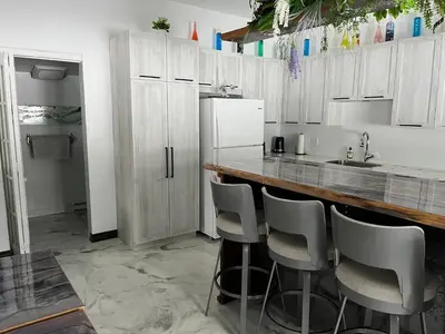 a kitchen with white cabinets and a bar with stools at Domaine Gagnon in Saint Sebastien