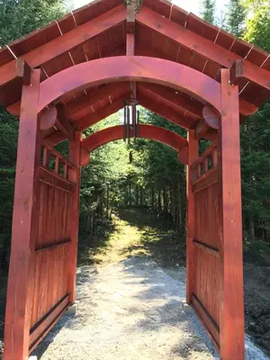 an entrance to a red gate in a forest at Domaine Gagnon in Saint Sebastien