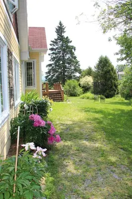 a house with a yard with flowers and a bench at La Maison Jaune D'Eastman in Eastman