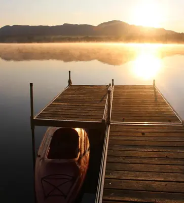 a boat sitting on the water next to a dock at La Maison Jaune D'Eastman in Eastman