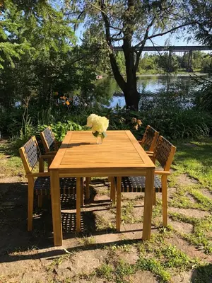 a wooden table with two chairs and a vase of flowers at La Maison Jaune D'Eastman in Eastman