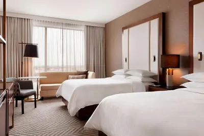 a hotel room with two beds and a chair at Sheraton Saint-Hyacinthe Hotel in Saint-Hyacinthe