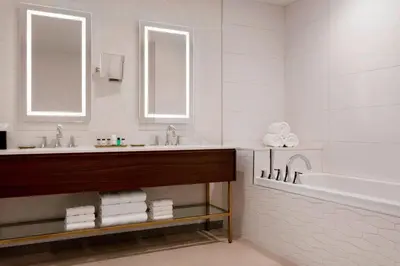 a bathroom with a tub and a sink and mirrors at Sheraton Saint-Hyacinthe Hotel in Saint-Hyacinthe