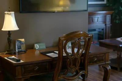a wooden desk with a chair and a lamp at Hotel Brossard in Brossard