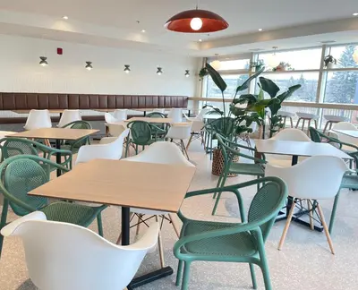 a cafeteria with tables and chairs and a plant at Hotel Brossard in Brossard