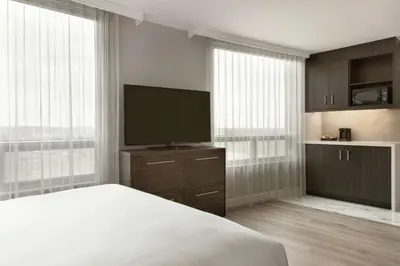 a bedroom with a bed and a flat screen tv at Embassy Suites By Hilton Montreal Airport in Pointe-Claire