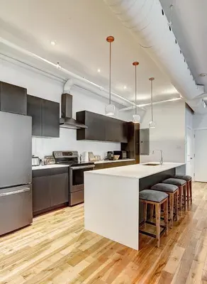 a kitchen with a white island in a room at Saint Sulpice Lofts by Bakan - Old Montreal in Montréal