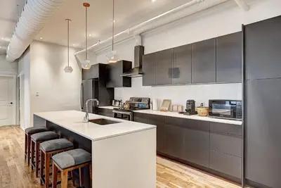 a kitchen with black and white cabinets and a counter at Saint Sulpice Lofts by Bakan - Old Montreal in Montréal