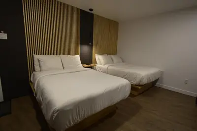 two beds in a hotel room with white sheets at Motel ANF in Drummondville