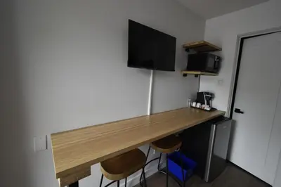 a desk in a room with two stools and a television at Motel ANF in Drummondville