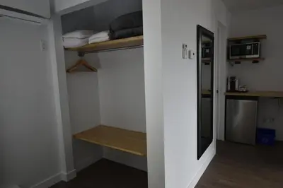 a small room with a bed and a shelf and a microwave at Motel ANF in Drummondville
